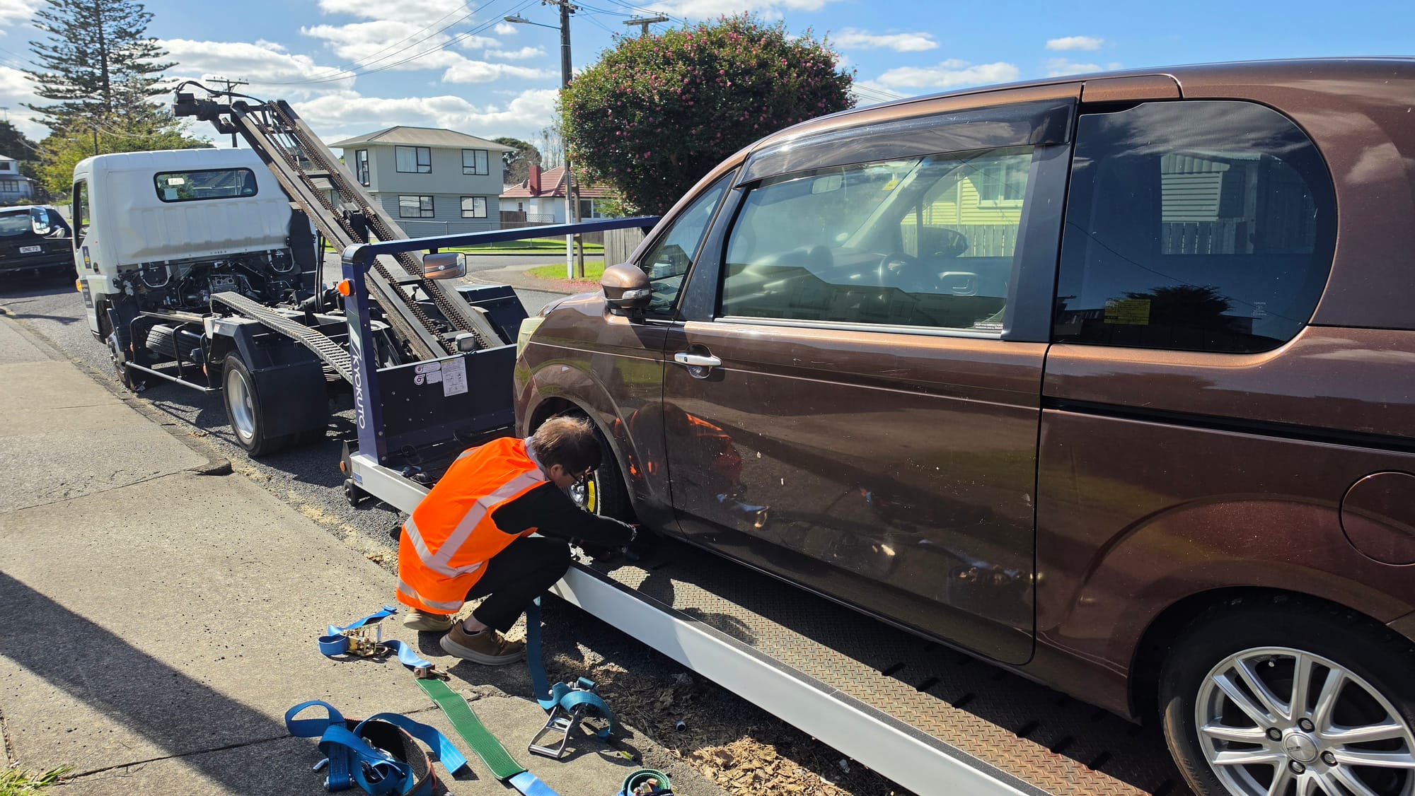 Drive1 Towing crew strapping a brown van to the flatbed kerbside in Auckland.